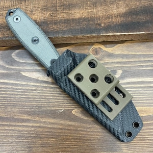 May include: A black and green knife with a carbon fiber sheath and a green nylon belt clip. The sheath has a textured surface and a black strap with a metal buckle.