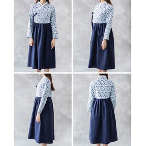 Op de afbeelding: Een jurk met lange mouwen met een bloemenpatroon op de top en een effen marineblauwe rok. De jurk heeft een wikkelhalslijn en een volle rok, wat zorgt voor een bescheiden en elegante uitstraling. De mouwen zijn lang en getailleerd.