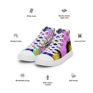 Puede incluir: Zapatillas blancas de lona de caña alta con un diseño abstracto colorido con fondo rosa, un sol sonriente y una calavera con dientes. Las zapatillas tienen cordones blancos, un cuello acolchado y un forro transpirable.