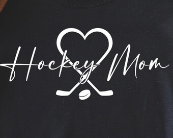 Könnte beinhalten: Schwarzes Sweatshirt mit dem weißen Schriftzug "Hockey Mom", mit einem Herz und Hockeyschlägern. Das Bild enthält auch einen braunen Hut und den Text "SVG PNG JPEG DXF EPS".