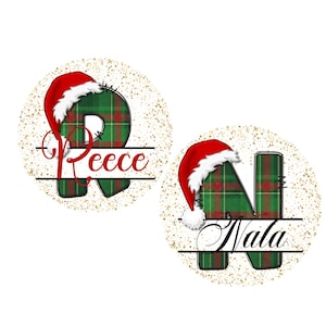 May include: Two circular Christmas ornaments with gold speckles. One features a green and red plaid letter "R" with a Santa hat and the name "Reece". The other has a green and red plaid letter "N" with a Santa hat and the name "Nala".