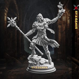 Può includere: Dettagliata statuetta fantasy grigia di un personaggio simile a un elfo che tiene in mano un bastone con una parte superiore a forma di stella e un globo fiammeggiante. La statuetta è su una base rocciosa con il testo "SYZ GAMES".