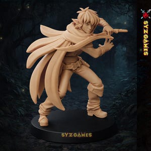 May include: A tan-colored figurine of a character in a dynamic pose, wearing a cloak and holding a weapon. The figure is on a black base, with the text "SYZ GAMES" visible. The background suggests a forest setting.