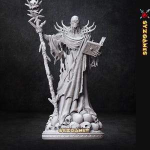 Op de afbeelding: Gedetailleerd grijs beeldje van een geklede figuur met een staf met een schedel en een boek. De figuur staat op een voet met schedels en de tekst "SYZ GAMES".
