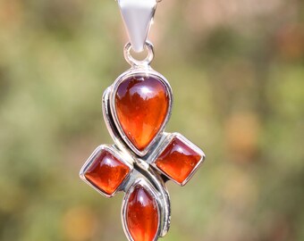 May include: A silver pendant necklace with a cross design featuring four orange carnelian gemstones.