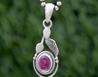 May include: A silver pendant necklace with a pink gemstone set in a silver bezel. The pendant features a delicate, leaf-like design.