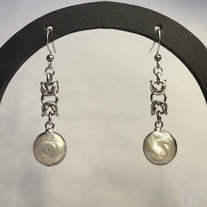 Pode incluir: Um par de brincos de prata com uma gota de p&eacute;rola e um design de corrente.