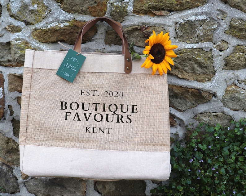 Natural Hessian Market Shopper Bag with leather handles, with the personalisation 'EST. 2020, BOUTIQUE FAVOURS, KENT' 
printed in black matte vinyl.