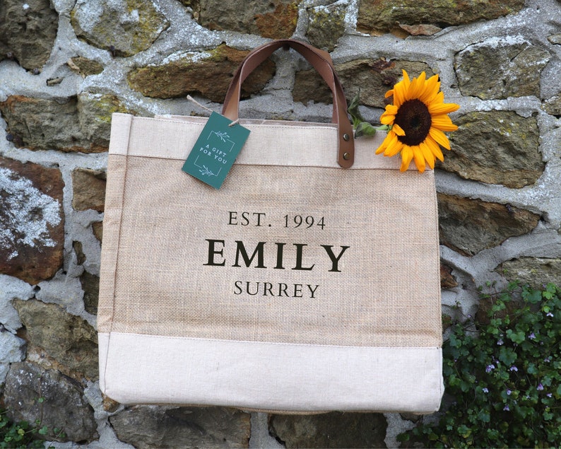 Natural Hessian Market Shopper Bag with leather handles, with the personalisation 'EST. 1994, EMILY, SURREY' printed in black matte vinyl.