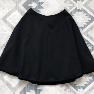 May include: A black, short, flowy skirt with a wide, rounded hem.