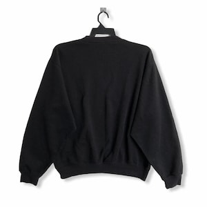 May include: Black sweatshirt with long sleeves and a crew neck.