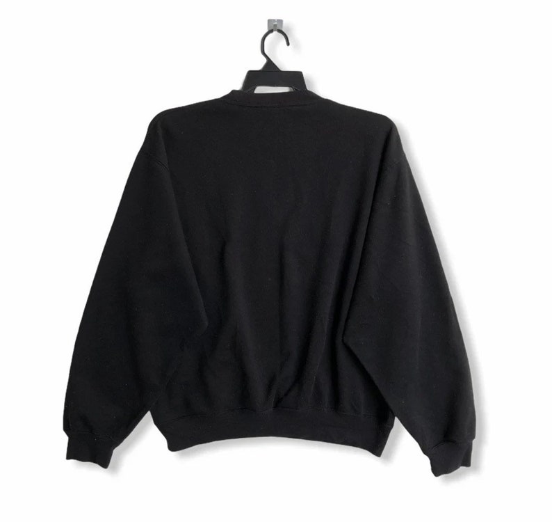 May include: Black sweatshirt with long sleeves and a crew neck.