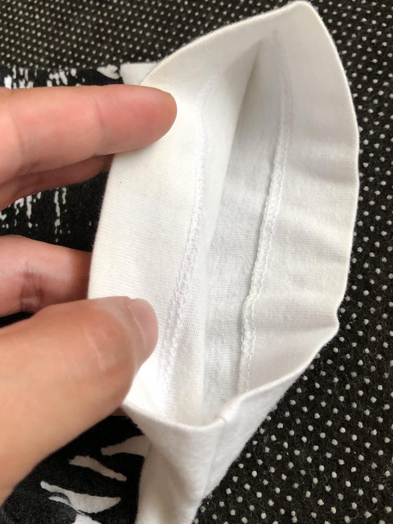 Puede incluir: Primer plano del interior de una camiseta blanca, mostrando las costuras alrededor del cuello.