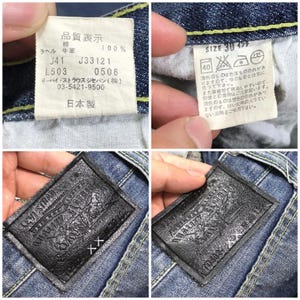 May include: Close-up of a pair of blue denim jeans with a leather patch that reads "Levi Strauss & Co. Quality Clothing" and a white tag with Japanese text and the size "30" in inches.