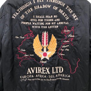 Puede incluir: Chaqueta bomber acolchada negra con texto y gr&aacute;ficos bordados. La parte trasera presenta un emblema alado, un mapa y el texto "YEA THOUGH I FLY THROUGH THE SKY OF THE SHADOW OF DEATH". La chaqueta tambi&eacute;n tiene la marca "AVIREX LTD."