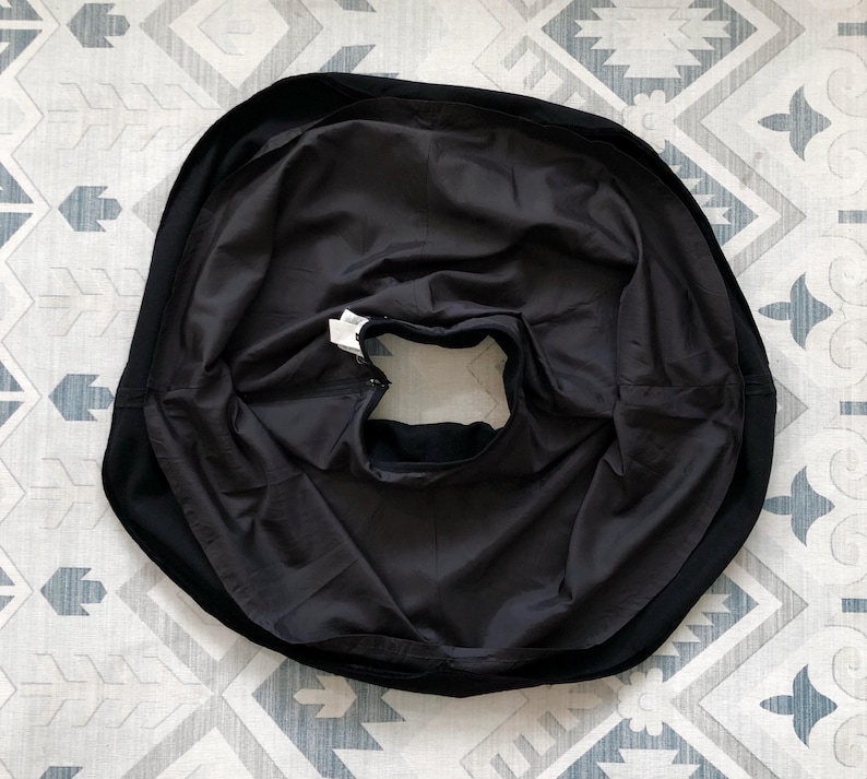 May include: Black circle skirt with a gathered waistband and a smooth, silky fabric.