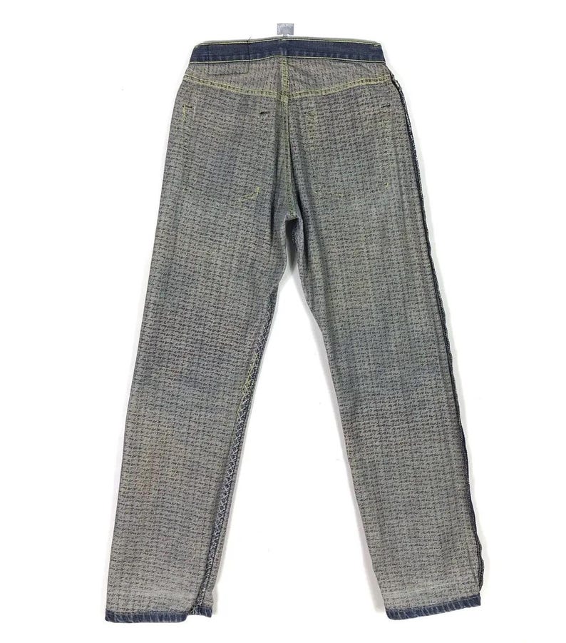 May include: A pair of blue denim jeans with a checkered pattern. The jeans have a dark blue waistband and a straight leg.