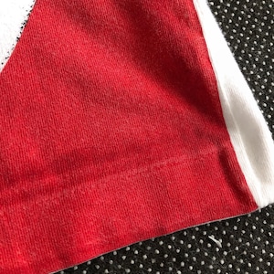 Puede incluir: Primer plano de una tela a rayas rojas y blancas. La tela est&aacute; hecha de un material suave y texturizado.