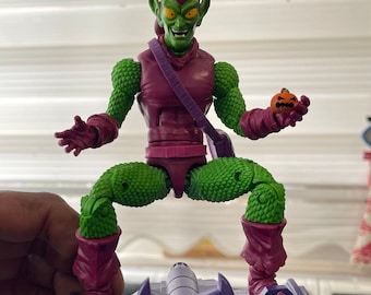 May include: Green Goblin action figure with a purple and green costume, riding a purple glider with a green pumpkin in his hand.