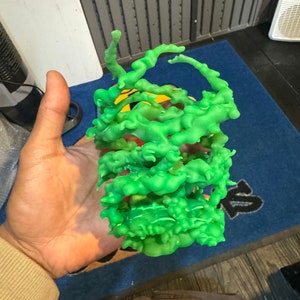以下が含まれることがあります： 緑色の3Dプリントされたオブジェクトで、ユニークで有機的な抽象的なデザインです。オブジェクトは、複雑で複雑な構造を作成するために、互いに絡み合い、接続された複数の緑色のプラスチック層で構成されています。