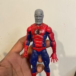 May include: A Spider-Man action figure with a custom gray head and beard. The figure is primarily red and blue, with a spider emblem on the chest. The figure is approximately 6 inches tall.
