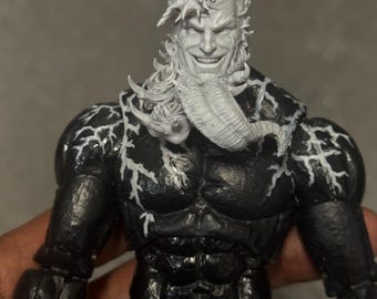 Puede incluir: Figura de acción negra de un personaje musculoso con detalles blancos y una cabeza esculpida detallada. La figura tiene una cara sonriente y cabello blanco. El cuerpo tiene una apariencia texturizada.