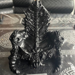 May include: A black, 3D printed, skeletal throne with a skull-like face and multiple skulls on the arms and back.