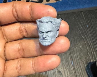 Puede incluir: Una escultura de cabeza de plástico gris de un hombre con el pelo corto y peinado y una expresión seria. La escultura de cabeza está detallada con rasgos faciales y arrugas.