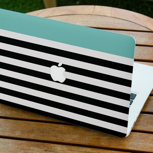 May include: A laptop computer with a black and white striped design and a teal blue stripe across the top. The Apple logo is visible on the lid.