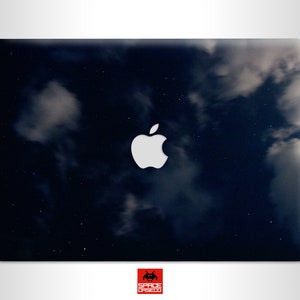 May include: A dark blue laptop skin with a white apple logo and a starry night sky design.