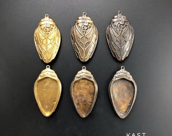 May include: Six metal cicada charms in different finishes. Three are gold-toned and three are silver-toned. The charms are detailed with intricate patterns and have a hollow back.