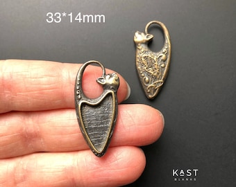 Könnte beinhalten: Zwei antike goldfarbene Metall-Katzenanhänger mit detailliertem Design. Die Anhänger sind 33 mm x 14 mm groß und haben eine strukturierte Oberfläche. Die Anhänger befinden sich auf einem schwarzen Hintergrund.