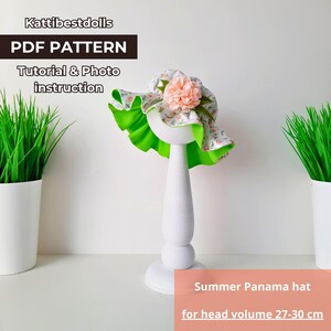 May include: A white and green floral patterned sun hat with a pink flower on top. The hat is on a white mannequin head. The text "Summer Panama hat for head volume 27-30 cm" is below the hat.