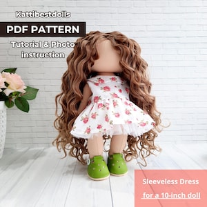 Pode incluir: Uma boneca com longos cabelos castanhos encaracolados usando um vestido branco sem mangas com um padrão floral rosa e sapatos verdes. A imagem inclui o texto "Kattibestdolls PDF PATTERN Tutorial & Photo instruction Vestido sem mangas para uma boneca de 25,4 cm."