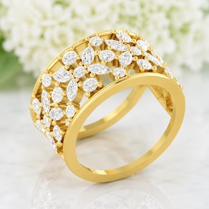 May include: A gold ring with a floral design, set with numerous clear, sparkling gemstones. The ring features a wide band with an openwork pattern, creating a delicate and elegant appearance. The gemstones are of varying sizes and shapes.