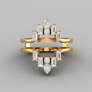 Puede incluir: Un anillo dorado con un diseño geométrico. El anillo presenta múltiples piedras preciosas claras, rectangulares y en forma de pera. Las piedras están dispuestas simétricamente, con una piedra redonda central y una piedra en forma de pera en la parte inferior.