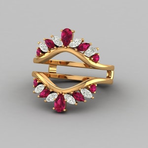 May include: A gold-colored ring guard with a double band design. The ring is adorned with alternating ruby-red and white gemstone accents, arranged in a floral pattern. The gemstones are pear and oval-shaped.
