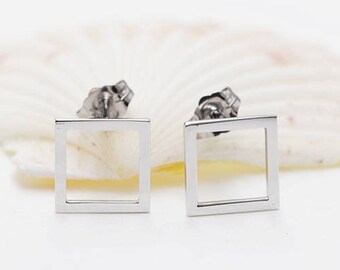 May include: A pair of silver square stud earrings. The earrings are simple and minimalist, with a thin, square frame.