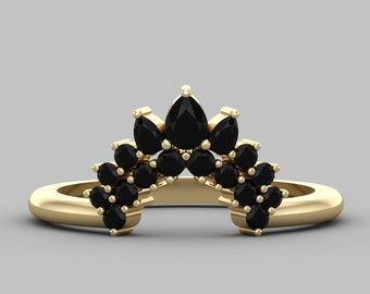 May include: A gold ring with a curved band and a row of black pear-shaped gemstones set in a crown shape.