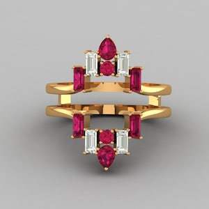 Könnte beinhalten: Ein goldfarbener Ring mit einem einzigartigen Design. Der Ring verfügt über eine Reihe von rechteckigen und birnenförmigen roten Edelsteinen sowie rechteckigen weißen Edelsteinen. Die Edelsteine sind in einem geometrischen Muster angeordnet.