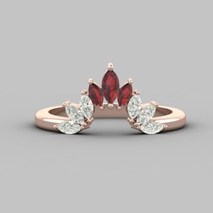 Peut inclure: Une bague en or rose avec une pierre centrale en rubis de forme marquise et de plus petits diamants de forme marquise de chaque côté. La bague est conçue pour être portée comme une alliance ou une bague empilable.