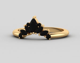 May include: A gold ring with a marquise-shaped black gemstone setting. The ring is designed with a crown-like shape, featuring multiple black gemstones arranged in a cascading pattern.