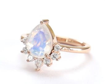May include: A pear-shaped moonstone ring set in rose gold with a halo of smaller diamonds.
