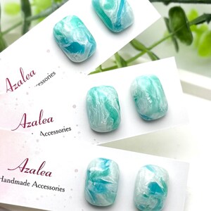 May include: Three pairs of rectangular, marbled-effect earrings in shades of turquoise, teal, and white. The earrings are displayed on white cards with the brand name "Azalea Accessories" printed in a script font.