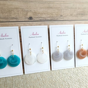 May include: Four pairs of handmade earrings on display cards. The earrings are made of resin and have a marbled effect. The colors are teal, white, gray, and brown.
