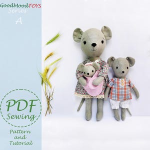 Könnte beinhalten: PDF-Nähmuster und Anleitung für eine dreiköpfige Familie aus grauen Stoffmäusen. Die Muttermaus hält ein kleineres graues Mäuschen in ihren Armen. Der Vatermaus steht neben ihnen. Die Spielzeuge sind aus Stoff und haben gestickte Details. Der Text "GoodMoodTOYS Series A" ist in der oberen linken Ecke des Bildes sichtbar.