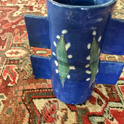 Studio shops art pottery vase, avant-garde lily of the valley flowers on blue