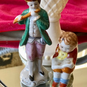 Occupied Japan Colonial man playing flute porcelain figurine, and a boy reading, 1940s