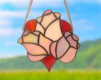 May include: A stained glass window hanging with a chain. The design is a red heart with three pink roses around it.