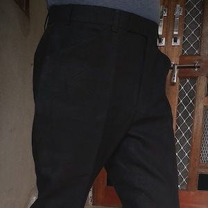 May include: A pair of black pants with a slight flare at the bottom. The person is wearing blue and red sneakers with white soles.